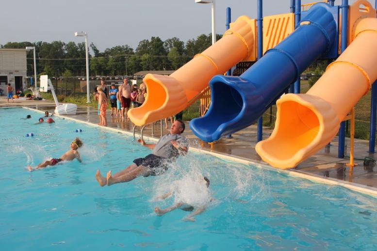 an adult and two children on a water slide about to enter a pool